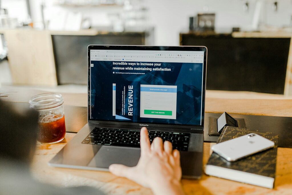Person clicking a clear get-started call-to-action on a laptop showing a revenue-focused landing page
